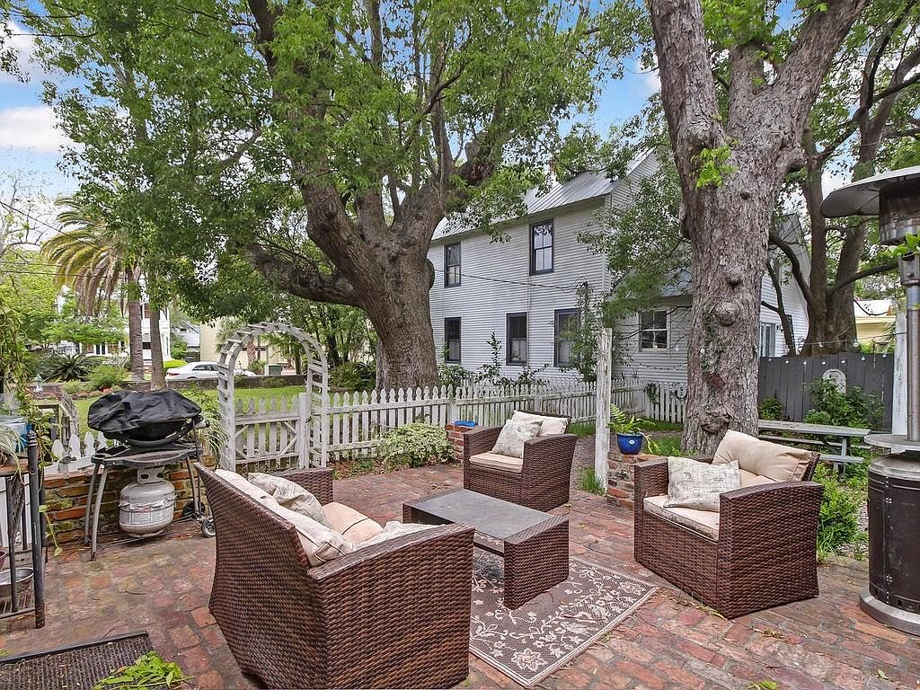 Outdoor brick patio with seating area beneath mature live oak trees