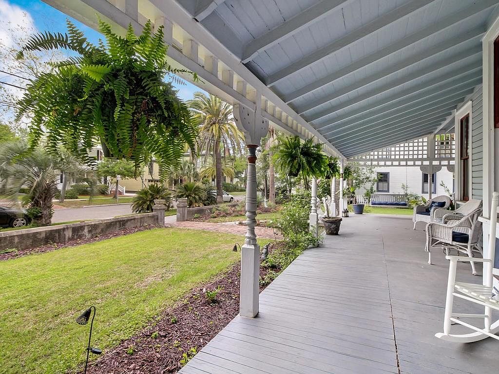Wrap-around porch with rocking chairs, looking out over the yard