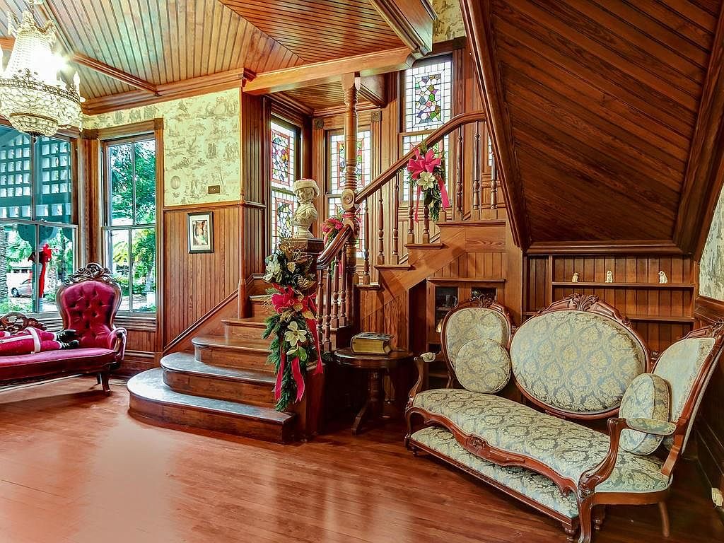 Grand entryway of the Swann-Kelly House featuring the mahogany staircase, inlaid wood ceiling, and stained glass windows